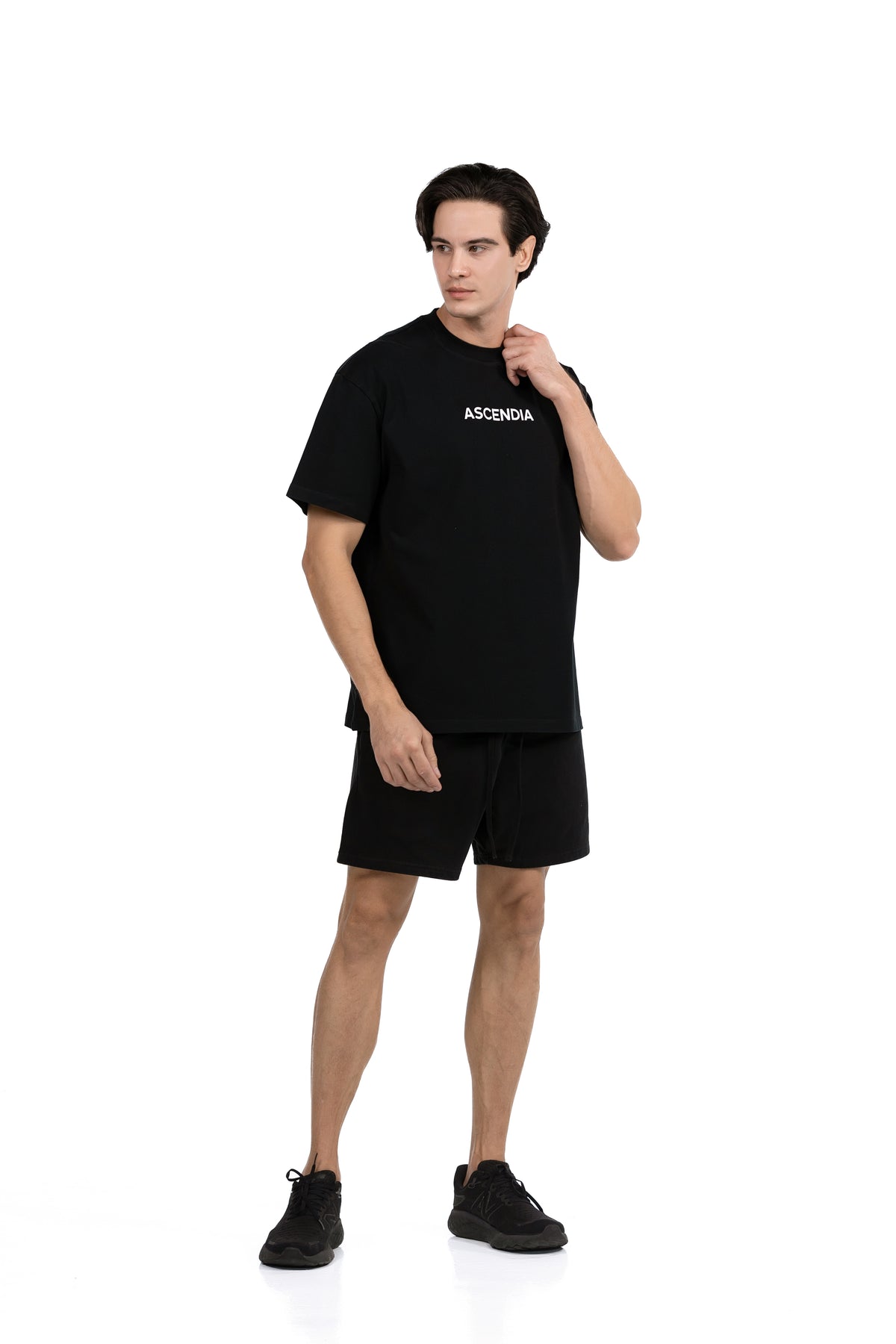 Workout Tee & Short Set in Black, three-quarter front view on male model with hand raised to the collar, Ascendia